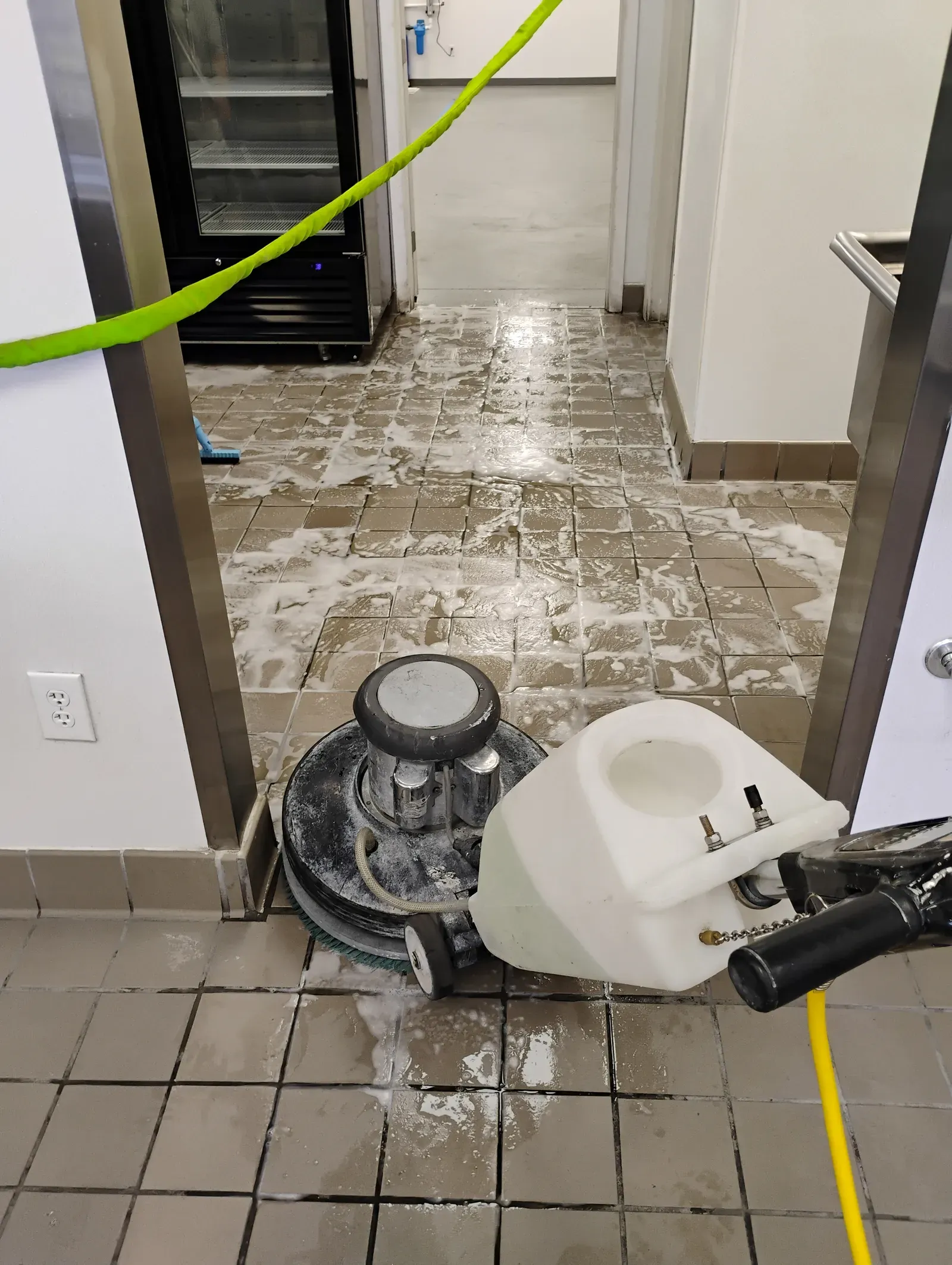 Rotary floor scrubber working heavy suds into the tile and grout of a Las Vegas commercial kitchen