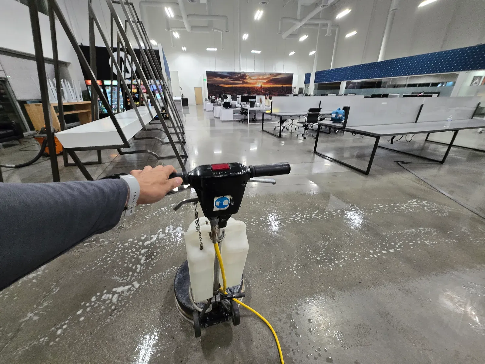 Technician running a floor buffing machine across polished concrete in a large Las Vegas commercial showroom