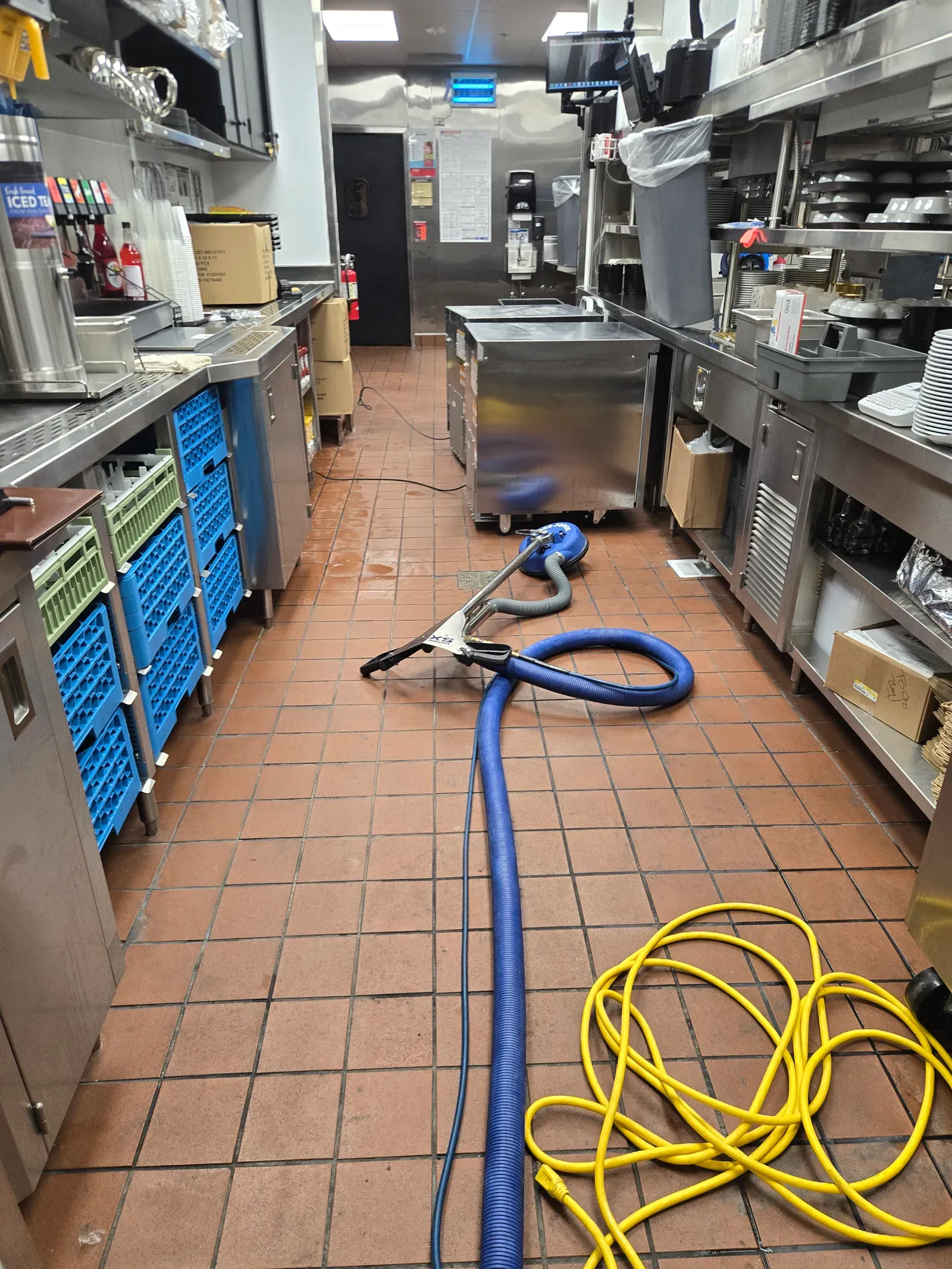 Spinner tile cleaning tool and extraction hose working the red quarry tile floor of a Las Vegas restaurant kitchen