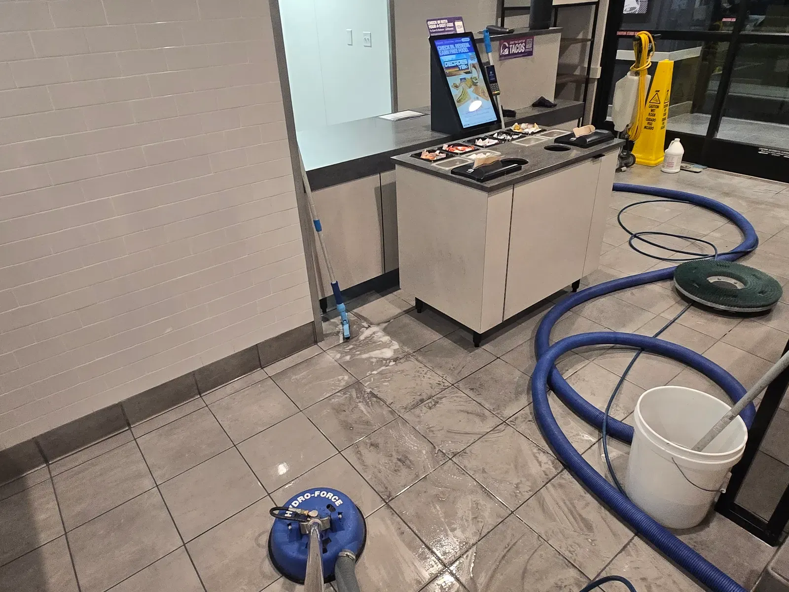 Spinner tool deep cleaning the tile floor at the front counter of a Las Vegas fast food restaurant
