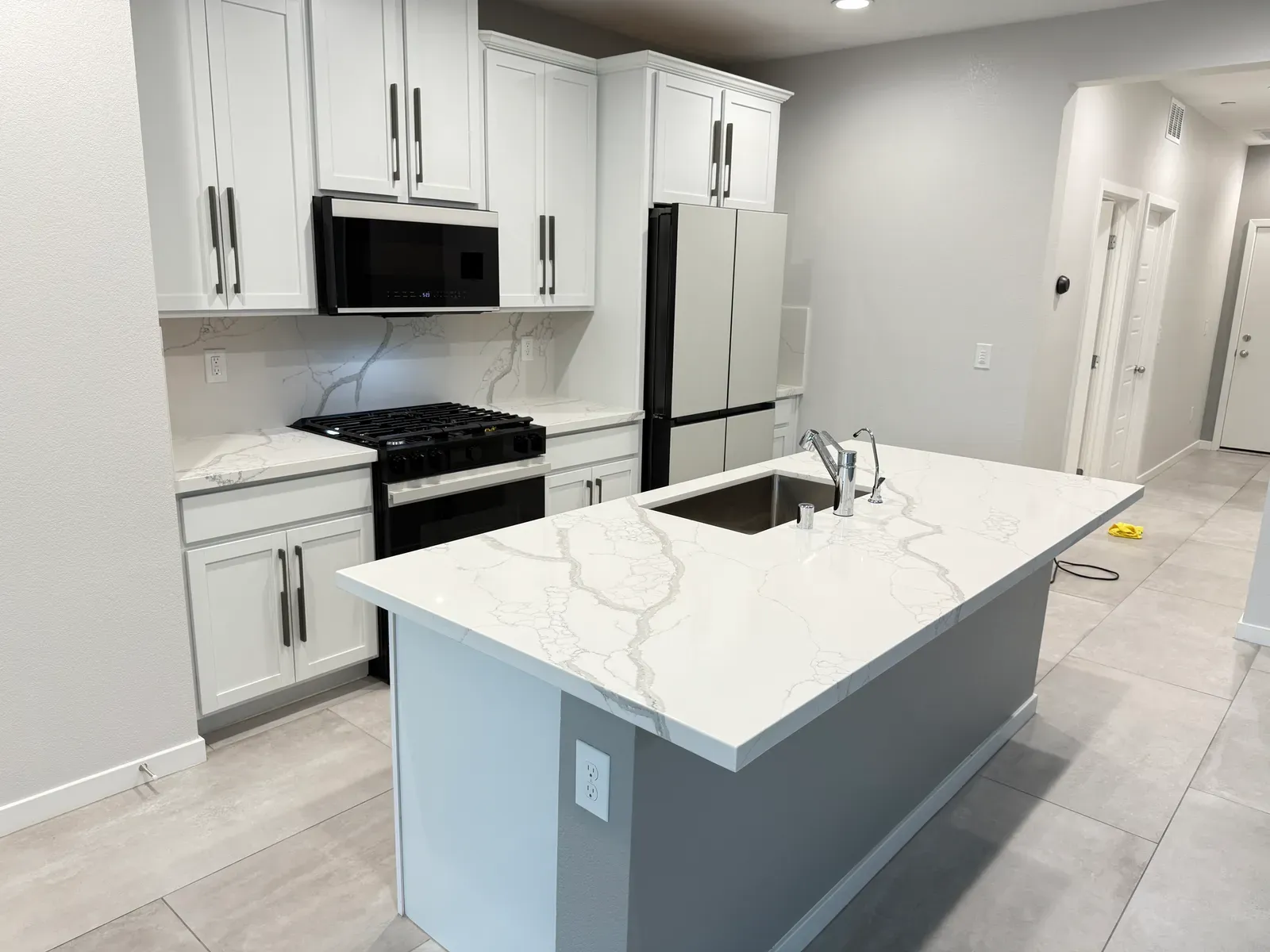 Freshly sealed white Calacatta quartz waterfall island in a bright Las Vegas kitchen