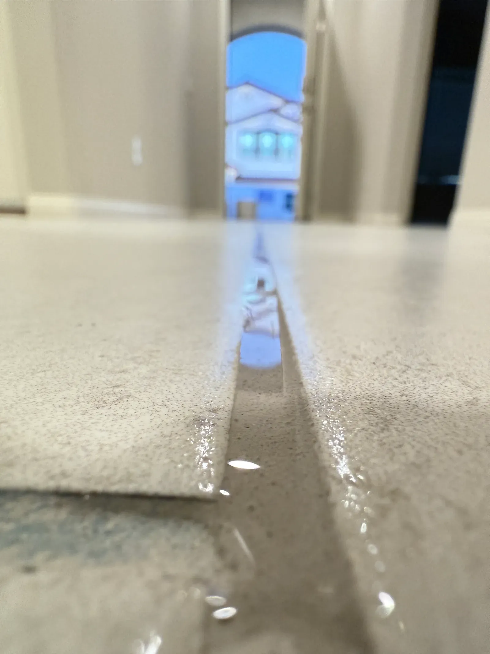 Low-angle close-up of fresh grout sealer beading along a large-format tile joint in a Las Vegas home