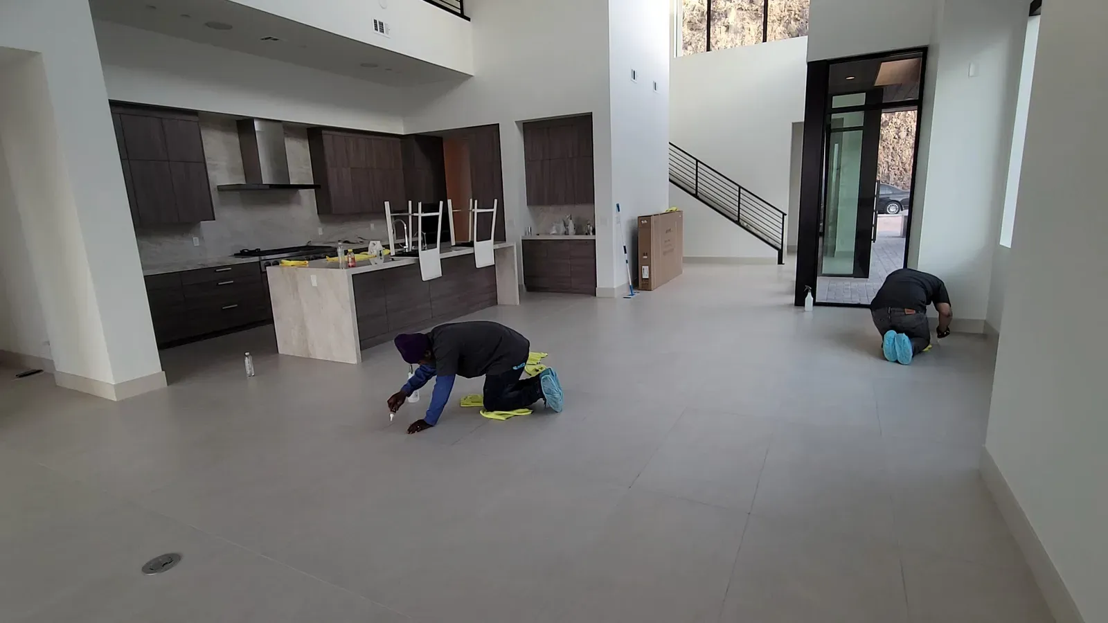 Two technicians hand-applying grout sealer to large-format tile flooring in an open Las Vegas home