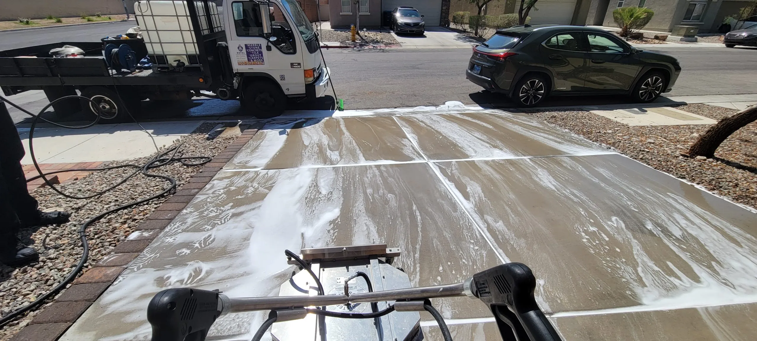 Power washing a residential driveway in Las Vegas with soap pretreatment