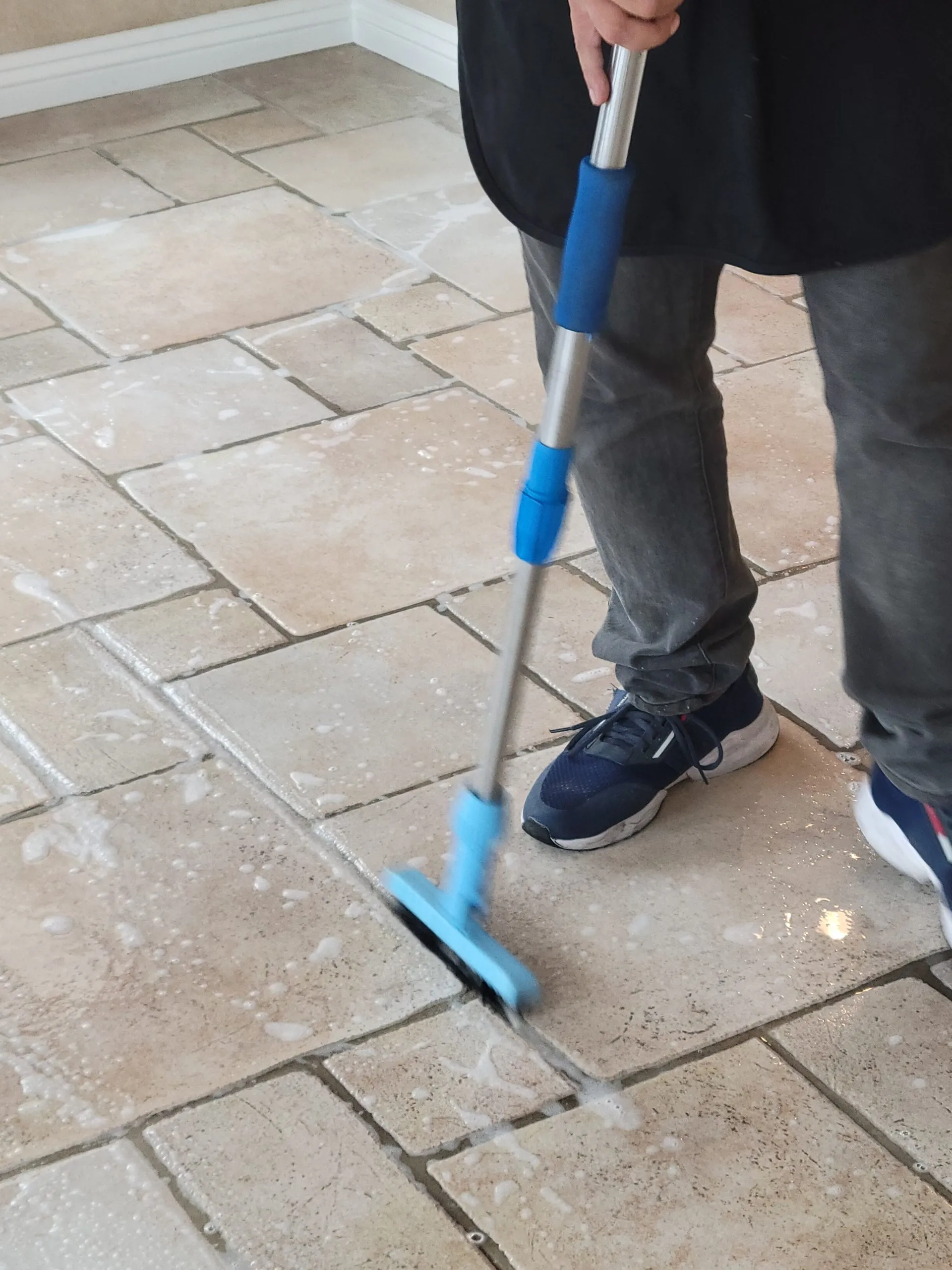 Pretreatment scrubbing on a travertine-style kitchen floor during tile and grout cleaning in Las Vegas