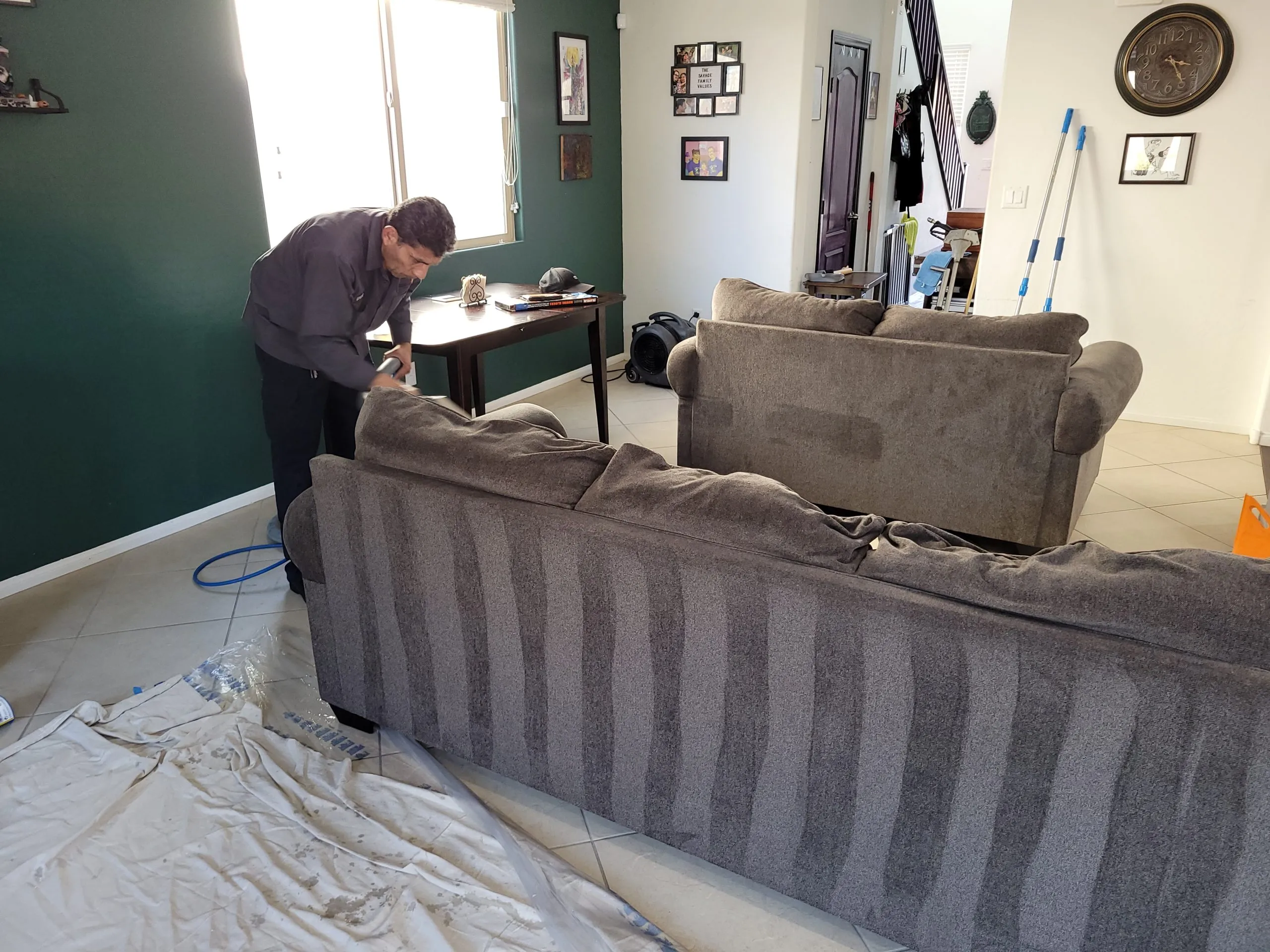 Cleaning a gray sectional sofa during professional upholstery service in a Las Vegas living room